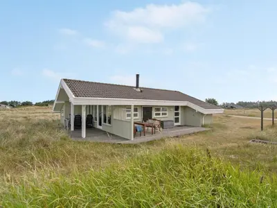 a small house with a deck in a field at Holiday Home Viktoria - 400m from the sea by Interhome in Løkken