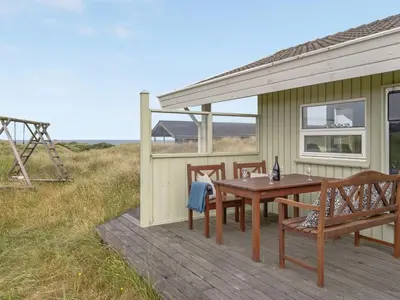 a wooden deck with a table and chairs on a house at Holiday Home Viktoria - 400m from the sea by Interhome in Løkken