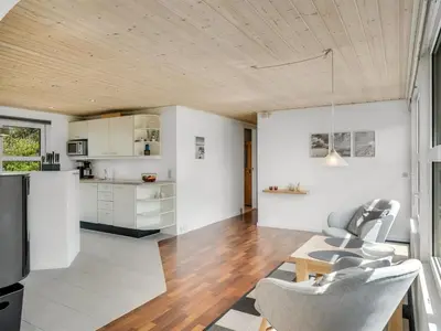 a kitchen and living room with white walls and wooden ceilings at Holiday Home Bengta - 200m from the sea by Interhome in Løkken