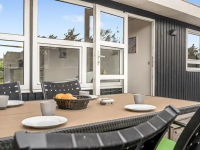 a wooden table with chairs and a basket of bread at Holiday Home Bengta - 200m from the sea by Interhome in Løkken