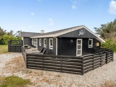 a black tiny house with a large deck at Holiday Home Bengta - 200m from the sea by Interhome in Løkken