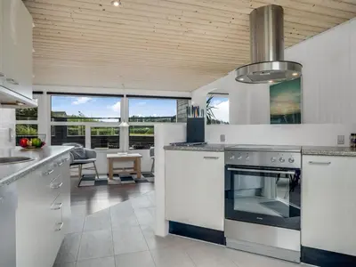 a kitchen with white cabinets and a stove top oven at Holiday Home Bengta - 200m from the sea by Interhome in Løkken