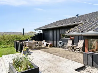 a wooden deck with a table and chairs on a house at Holiday Home Danica - 175m from the sea by Interhome in Løkken
