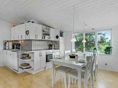 a kitchen with white cabinets and a table and chairs at Holiday Home Stina - 250m from the sea by Interhome in Løkken