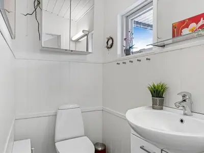 a bathroom with a sink and a toilet and a mirror at Holiday Home Stina - 250m from the sea by Interhome in Løkken