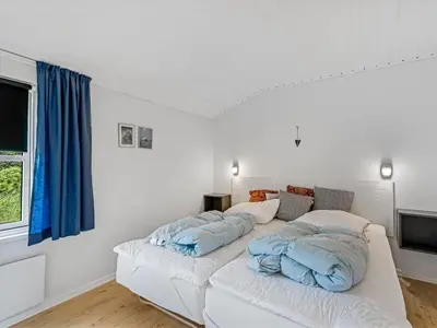 a bed with blue pillows on it in a room at Holiday Home Stina - 250m from the sea by Interhome in Løkken
