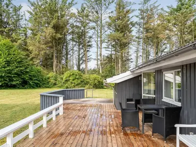 a house with a deck next to a yard at Holiday Home Dimo - 700m from the sea by Interhome in Løkken