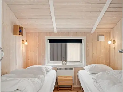 two beds in a room with a window at Holiday Home Dimo - 700m from the sea by Interhome in Løkken