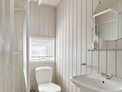 a bathroom with a toilet and a sink and a mirror at Holiday Home Solvejg - 150m from the sea by Interhome in Løkken