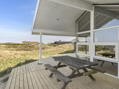 a wooden deck with a picnic table and a window at Holiday Home Solvejg - 150m from the sea by Interhome in Løkken