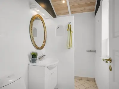 a white bathroom with a mirror and a sink at Holiday Home Kasperi - 250m from the sea by Interhome in Løkken