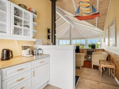 a kitchen with white cabinets and a dining room at Holiday Home Kasperi - 250m from the sea by Interhome in Løkken
