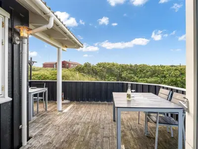 a patio with a table and chairs on a deck at Holiday Home Kasperi - 250m from the sea by Interhome in Løkken