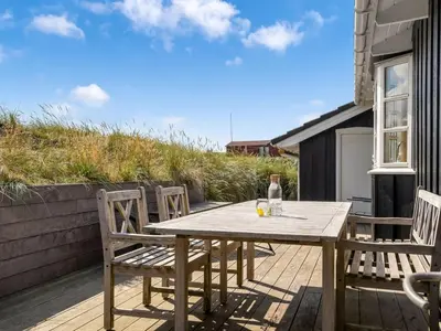 a wooden table and chairs on a wooden deck at Holiday Home Kasperi - 250m from the sea by Interhome in Løkken