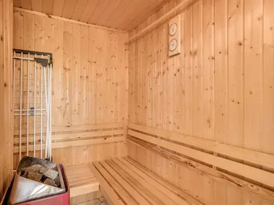 a sauna with a bench and a clock on the wall at Holiday Home Kasperi - 250m from the sea by Interhome in Løkken