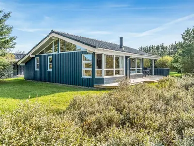 a green house with a blue facade at Holiday Home Terho - 1km from the sea by Interhome in Løkken