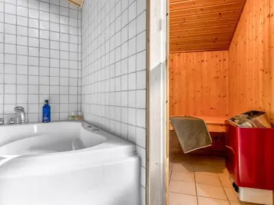 a bathroom with a tub and a red trash can at Holiday Home Terho - 1km from the sea by Interhome in Løkken