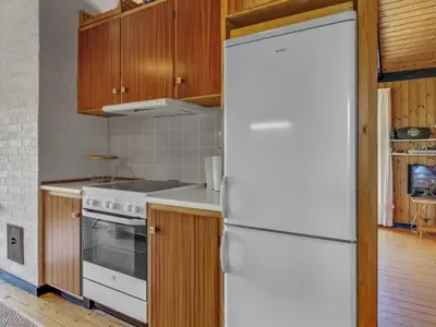 a white refrigerator in a kitchen with wooden cabinets at Holiday Home Tulir - 300m from the sea by Interhome in Løkken
