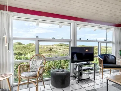 a living room with a large window and a television at Holiday Home Anne - 100m from the sea by Interhome in Løkken