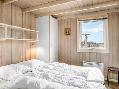 a bedroom with a large white bed and a window at Holiday Home Anne - 100m from the sea by Interhome in Løkken