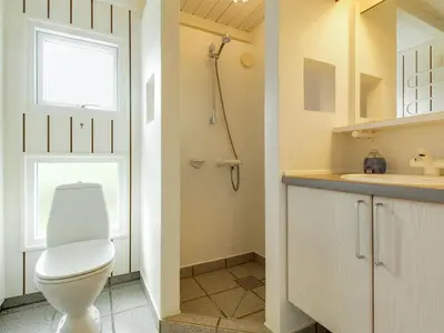 a white bathroom with a toilet and a sink at Holiday Home Avni - 200m from the sea by Interhome in Løkken
