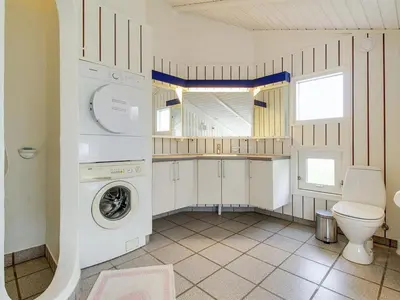 a bathroom with a washing machine and a toilet at Holiday Home Avni - 200m from the sea by Interhome in Løkken
