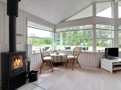 a living room with a fireplace and a table and chairs at Holiday Home Siljana - 1km from the sea by Interhome in Løkken