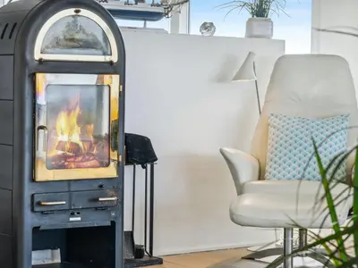 a living room with a fireplace and a chair at Holiday Home Alyssa - 300m from the sea by Interhome in Løkken