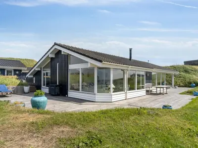 a house with large windows and a deck at Holiday Home Alyssa - 300m from the sea by Interhome in Løkken