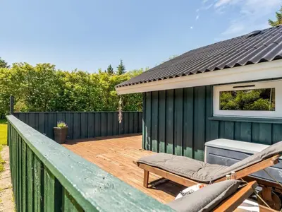 a deck with a chair and a house at Holiday Home Seda - 600m from the sea by Interhome in Løkken