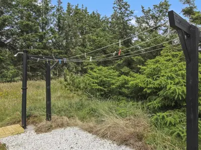 a red bird sitting on a wire in a field at Holiday Home Jens - 425m from the sea by Interhome in Løkken