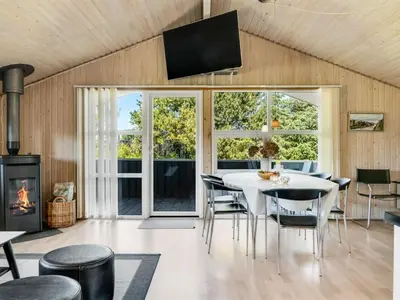 a dining room with a table and chairs and a fireplace at Holiday Home Guja - 1km from the sea by Interhome in Løkken