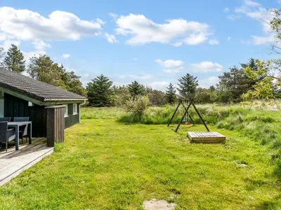 a yard with a swing and a house at Holiday Home Aponi - 400m from the sea by Interhome in Løkken
