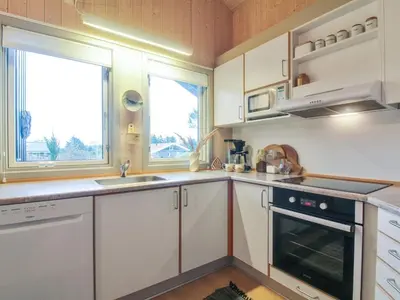 a kitchen with white cabinets and a sink and a stove at Holiday Home Lovisa - 500m from the sea by Interhome in Løkken