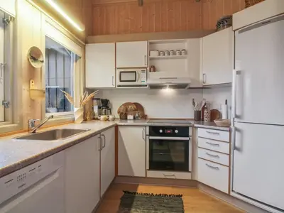 a kitchen with white cabinets and a sink and a refrigerator at Holiday Home Lovisa - 500m from the sea by Interhome in Løkken