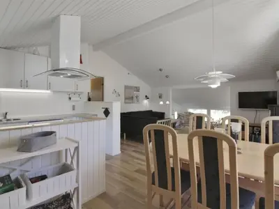 a kitchen and living room with a table and chairs at Holiday Home Eden - 800m from the sea by Interhome in Løkken