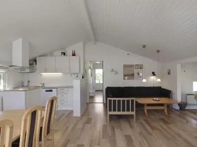 a kitchen and living room with a couch and a table at Holiday Home Eden - 800m from the sea by Interhome in Løkken