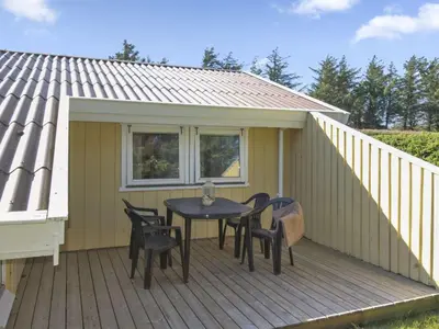a wooden deck with a table and chairs on it at Holiday Home Eden - 800m from the sea by Interhome in Løkken