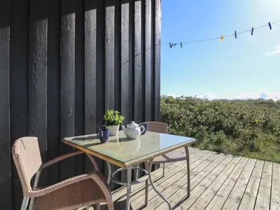 a table and chairs on a wooden deck with a view at Holiday Home Lauri - 350m from the sea by Interhome in Løkken