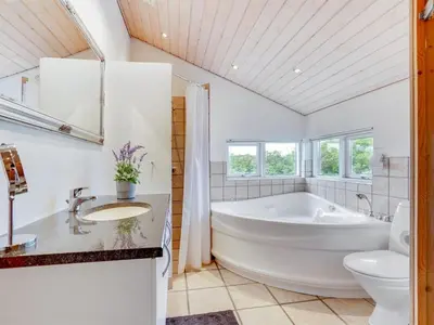 a bathroom with a tub and a toilet and a sink at Holiday Home Lauri - 350m from the sea by Interhome in Løkken