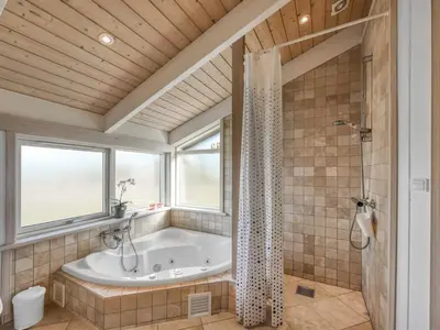 a bathroom with a tub and a window at Holiday Home Asol - 650m from the sea by Interhome in Løkken