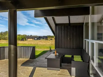 a patio with a bench and a table on a deck at Holiday Home Asol - 650m from the sea by Interhome in Løkken