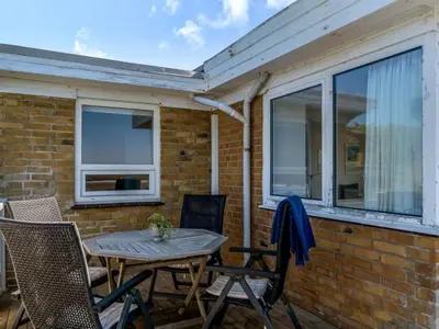 a patio with a table and chairs on a brick wall at Holiday Home Mielikki - 200m from the sea by Interhome in Løkken
