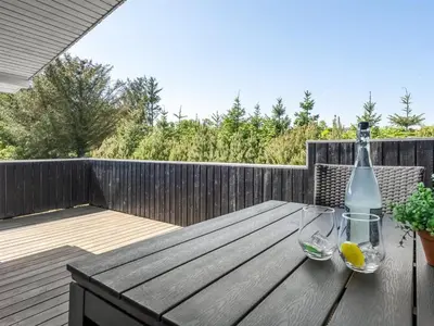 a bottle of wine and two glasses on a wooden table at Holiday Home Tonja - 300m from the sea by Interhome in Løkken
