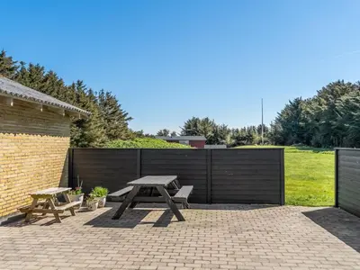 a picnic table and benches on a brick patio at Holiday Home Nayeli - 275m from the sea by Interhome in Løkken