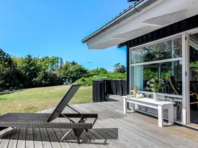 a patio with a bench and a table and chairs at Holiday Home Elvan - 450m from the sea by Interhome in Løkken