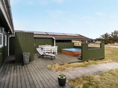 a wooden deck with a bench and a hot tub at Holiday Home Elco - 450m from the sea by Interhome in Løkken