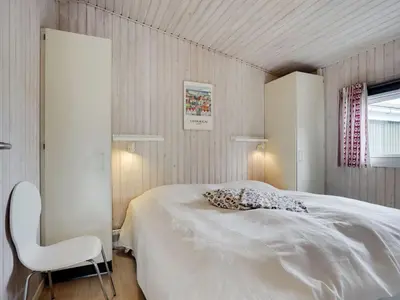 a bedroom with a white bed and a white chair at Holiday Home Elco - 450m from the sea by Interhome in Løkken