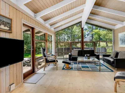 a living room with large windows and a flat screen tv at Holiday Home Paulette - 450m from the sea by Interhome in Løkken