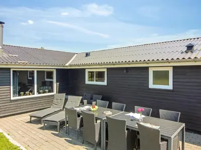a patio with a table and chairs in front of a house at Holiday Home Susan - 600m from the sea by Interhome in Løkken